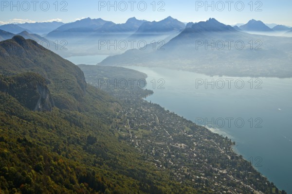 View from the summit of Mont Baron over the village of Veyrier-du-Lac to Lac dAnnecy in autumn mist to the chain of peaks of the Savoy Alps, Lake of Annecy, Annecy, Haute-Savoie, France, Europe