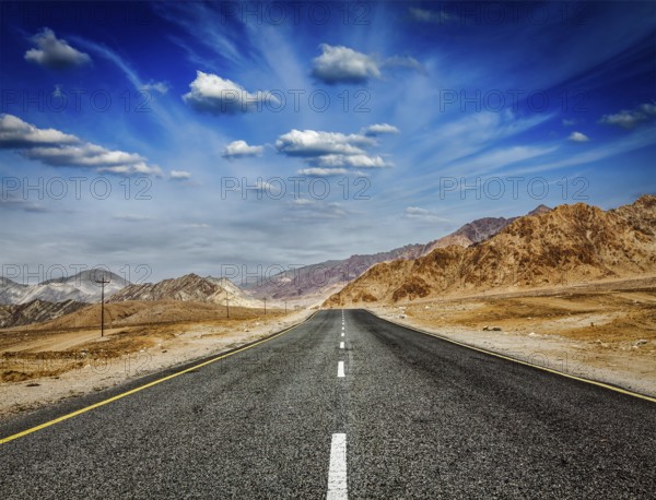 Travel forward concept background, road in Himalayas with mountains and dramatic clouds. Ladakh, Jammu and Kashmir, India, Asia