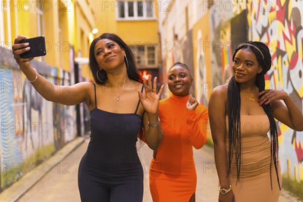 San Sebastián, Gipuzkoa Spain, February 2021: Three girls taking a selfie. Fashionable urban style with three black African girls on a city street, tight dresses