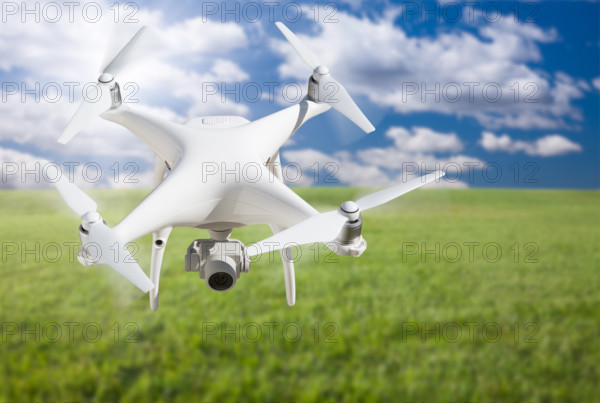 Unmanned aircraft system (UAV) quadcopter drone in the air over grass