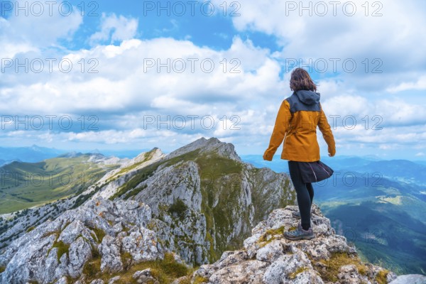 Mount Aizkorri 1523 meters, the highest in Guipúzcoa. Basque Country. Ascent through San Adrián and return through the Oltza fields. A young woman in yellow looking at the views on top