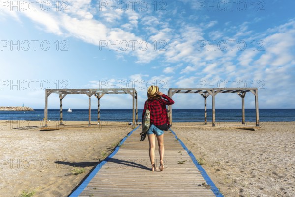 A young tourist on the wooden walkway of San Jose beach in the town of Nijar, Almería. Andalusian coast in Cabo de Gata. Spain