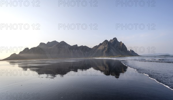 Black lava beach, sandy beach and sea, mountains Klifatindur reflected in the water, Eystrahorn and Kambhorn, headland Stokksnes, mountain range Klifatindur, Austurland, East Iceland, Iceland, Europe
