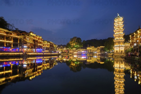 Chinese tourist attraction destination, Feng Huang Ancient Town (Phoenix Ancient Town) on Tuo Jiang River with Wanming Pagoda illuminated at night. Hunan Province, China, Asia