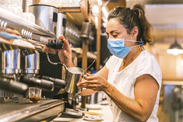 A waitress with a face mask in a bar. New normality, security measures after the coronavirus pandemic, social distance, covid-19. Preparing a coffee