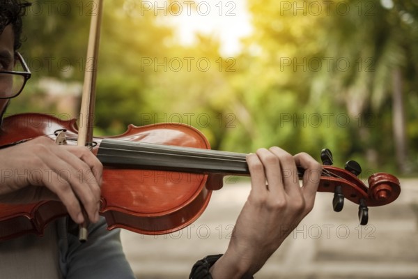 Close up of hands playing the violin outdoors. Violinist artist playing a melody outdoors, Portrait of man playing violin at sunset. Image of a person playing the violin outdoors