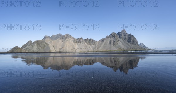 Black lava beach, sandy beach and sea, mountains Klifatindur reflected in the water, Eystrahorn and Kambhorn, headland Stokksnes, mountain range Klifatindur, Austurland, East Iceland, Iceland, Europe