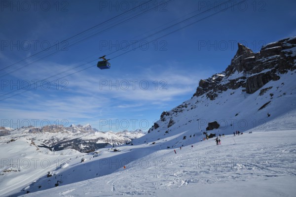 View of a ski resort piste with people skiing in Dolomites in Italy with cable car ski lift. Ski area Arabba. Arabba, Italy, Europe