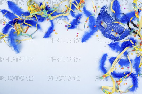 Blue mask and colourful ribbons with feathers and confetti on a light blue background, carnival
