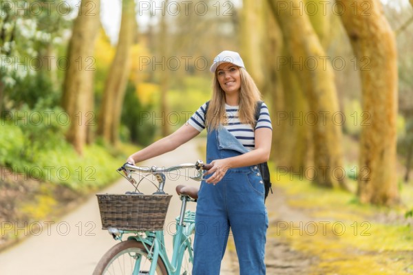 Young woman walking alongside her bicycle in a vibrant park, soaking up the warmth of a sunny day while enjoying the beauty of nature