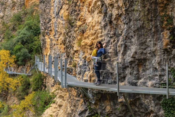 Very happy woman and son walking along the metal walkways of the Vero River path in Alquezar. Pyrenees