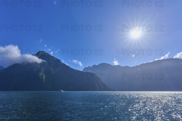 Bright sun over mountains and an expanse of water, summer, Milford Sound, Te Anau, Fiordland National Park, South Island, New Zealand, Oceania
