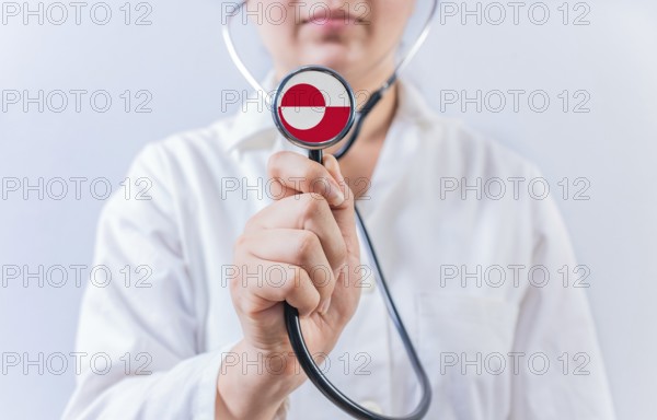 Female doctor holding stethoscope with Greenland flag. National Health System of Greenland