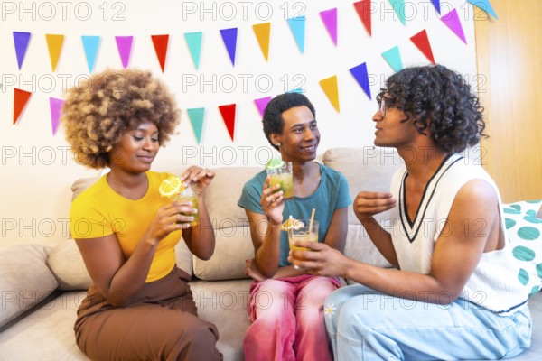 Multi-ethnic friends drinking cocktails partying at home sitting on the sofa chatting