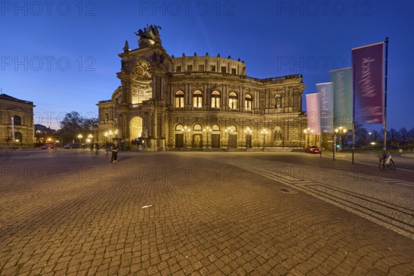 Semperoper, architectural style neo-renaissance, architect Gottfried Semper, flags with programme of the Dresden State Opera, motion blur, evening blue hour, Theaterplatz, Dresden, state capital, independent city, Saxony, Germany, Europe