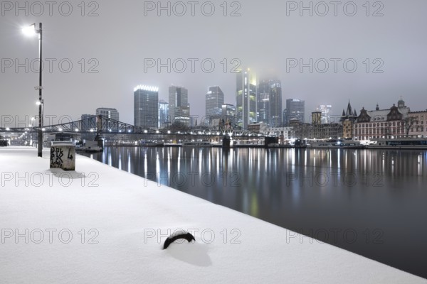 The skyscrapers of Frankfurt's banking skyline rise up from the snow-covered city centre into the low-hanging cloud cover. Frankfurt am Main, Hesse, Germany, Europe
