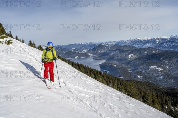 Skiers skiing down the Simetsberg, view of Walchensee and mountain panorama, Estergebirge, Bavarian Prealps, Bavaria Germany