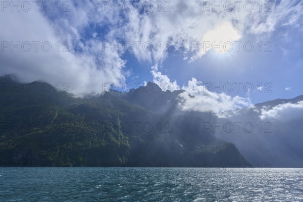 Sunshine over mountains with partial cloud cover and blue water, summer, Milford Sound, Te Anau, Fiordland National Park, South Island, New Zealand, Oceania