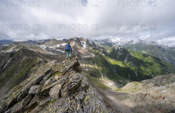Mountaineer on a steep rocky ridge, on the summit of the Lasörling, view of mountains of the Venediger group, Lasörling group, Hohe Tauern National Park, East Tyrol, Tyrol, Austria, Europe