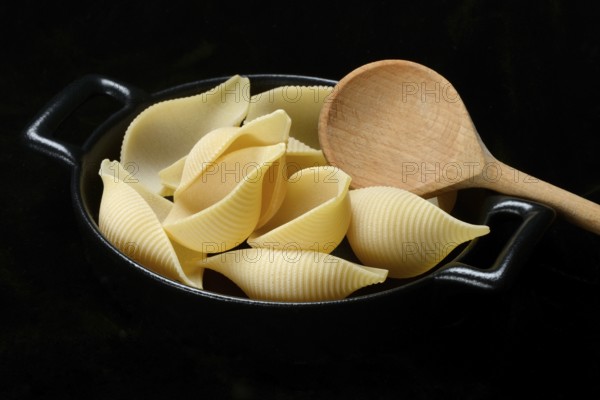 Conchiglione, Italian pasta in pot with cooking spoon