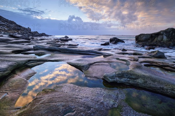 Rocks on beach of fjord of Norwegian sea in winteron sunset. Utakliev beach, Lofoten islands, Norway, Europe