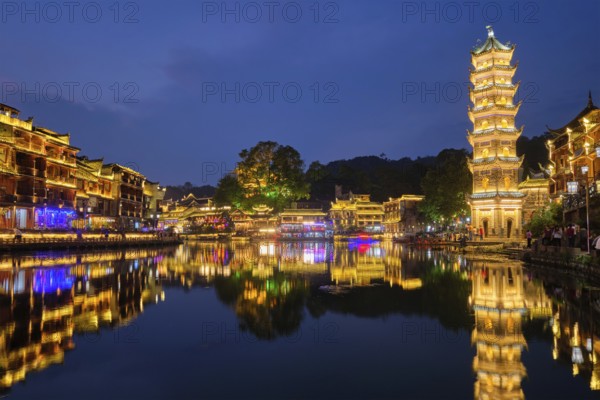 Chinese tourist attraction destination, Feng Huang Ancient Town (Phoenix Ancient Town) on Tuo Jiang River with Wanming Pagoda illuminated at night. Hunan Province, China, Asia