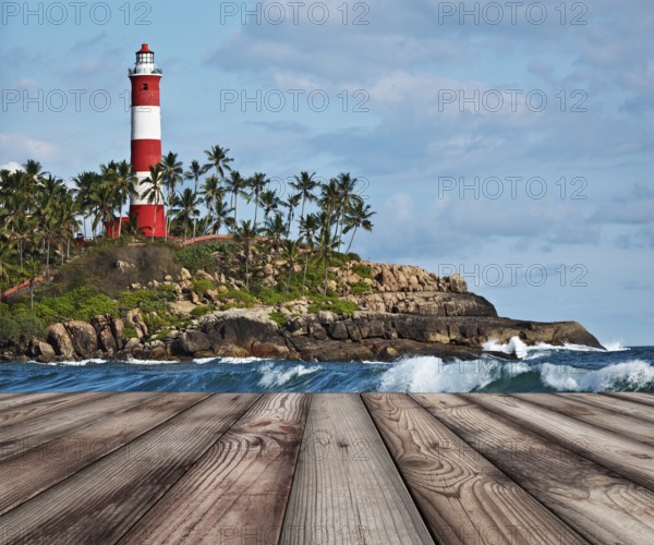 Wood planks floor with old lighthouse and sea waves in background