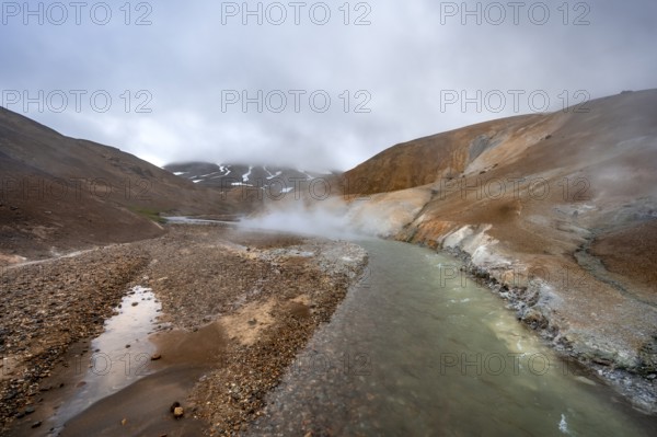 Steaming stream between colourful rhyolite mountains with snowfields, Hveradalir geothermal area, Kerlingarfjöll, Icelandic highlands, Iceland, Europe