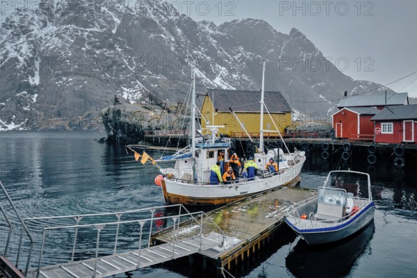 NUSFJORD, NORWAY, MARCH 25, 2017: Fishermen and fishing boat on pier in Nusfjord fishing village, Lofoten islands, Norway, Europe