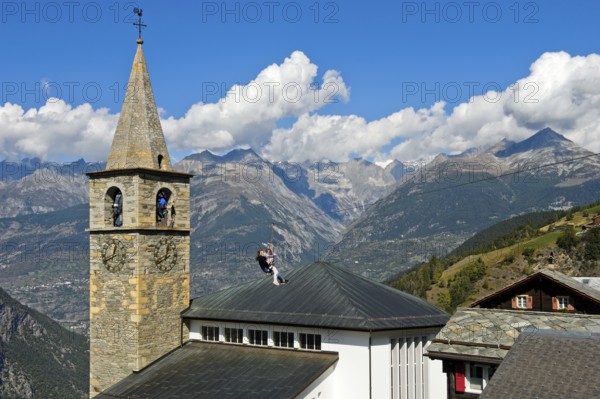 Test of courage at the Chinderwältfäscht, Children's World Festival: Two girls slide down a zip wire from the church tower to the ground, Chinderwältfäscht, Children's World Festival, Heath village Visperterminen, Valais, Switzerland, Europe