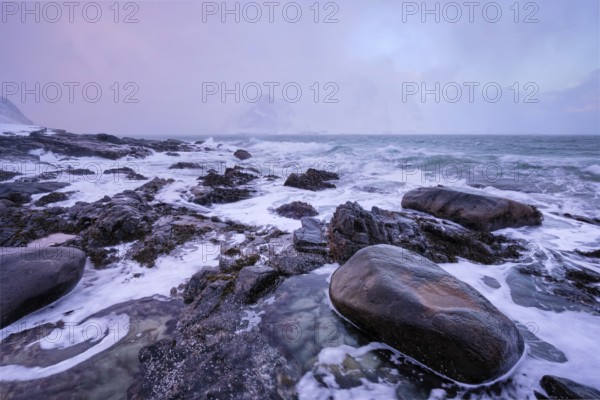 Beach of Norwegian sea on rocky coast in fjord on sunset in winter. Vareid beach, Lofoten islands, Norway, Europe