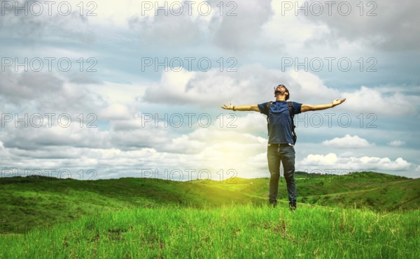 Adventurous man spreading his arms in the countryside. Man with backpack on a hill spreading his arms. Explorer man spreading his arms on a hill. Lifestyle of adventurous man in the field