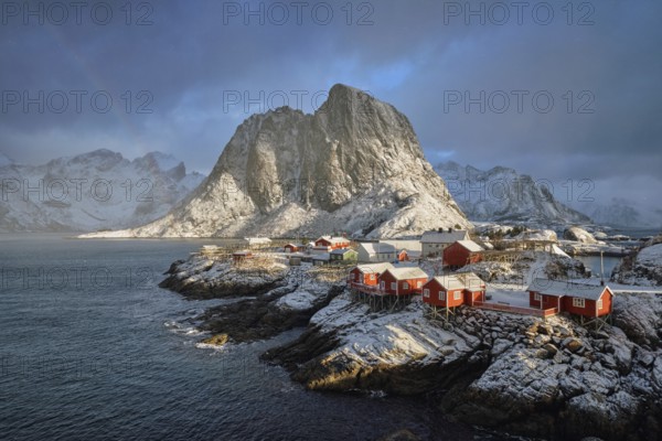 Hamnoy fishing village on Lofoten Islands, Norway with red rorbu houses. With falling snow in winter and rainbow