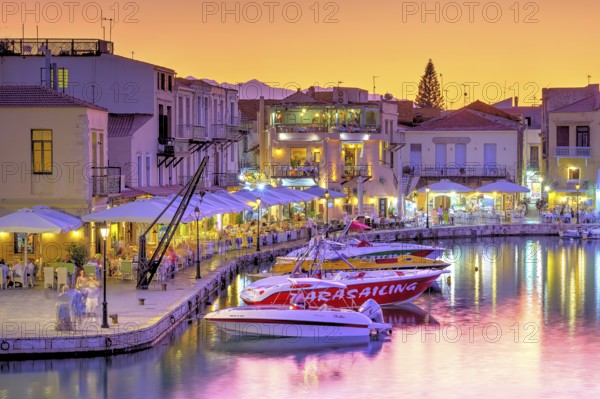 Venetian harbour, dusk, night shots, orange sky, colourful rows of houses, water reflection, artificial light, boats, Rethimnon, central Crete, island of Crete, Greece, Europe