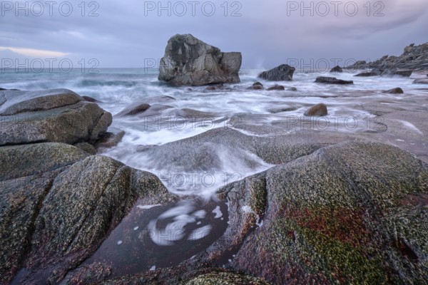 Rocks on beach of fjord of Norwegian sea in winteron sunset. Utakliev beach, Lofoten islands, Norway, Europe