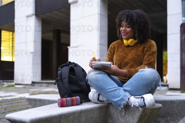 Portrait of black ethnic girl sitting in college doing classwork or studying for an exam