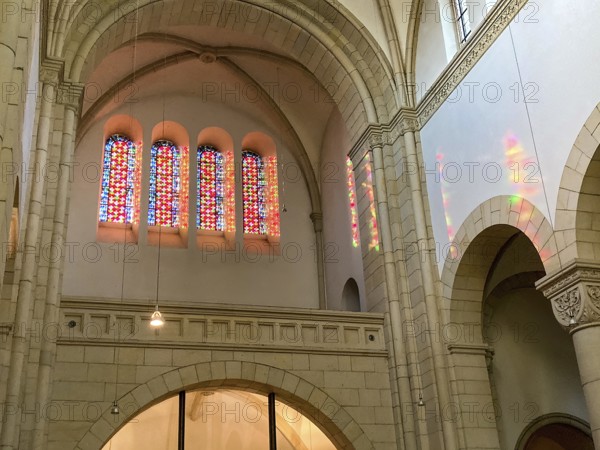 Sun shines through four stained glass windows above main portal of Benedictine Abbey Gerleve casts colourful light into nave, Gerleve, Münsterland, North Rhine-Westphalia, Germany, Europe