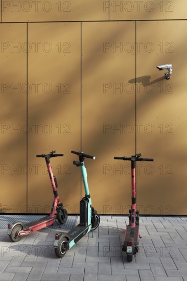 Three e-scooters correctly parked on the pavement, under a surveillance camera, Düsseldorf, North Rhine-Westphalia, Germany, Europe