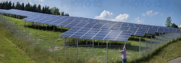 Man photographing a fenced photovoltaic plant, Pfronten, Allgäu, Bavaria, Germany, Europe