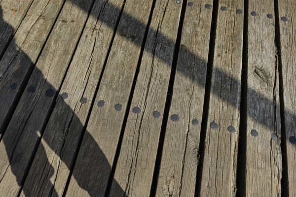 Shadow cast by a person and wooden planks, heritage-protected wooden bascule bridge over the Trebel near Nehringen, Mecklenburg-Western Pomerania, Germany, Europe