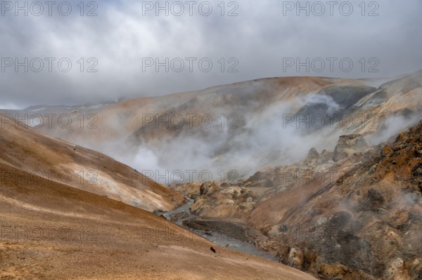 Steaming stream between colourful rhyolite mountains and snowfields, Hveradalir geothermal area, Kerlingarfjöll, Icelandic Highlands, Iceland, Europe