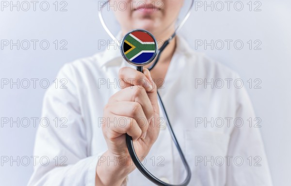 Female doctor holding stethoscope with South Africa flag. National Health System of South Africa