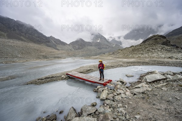 Mountaineer on a bridge over a glacial river of the glacier Glacier de Cheilon, Valais, Western Alps Switzerland