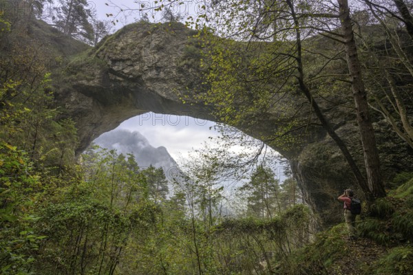 Woman photographing stone arch Ponte dell Orco, Ospedaletto, Trentino, Italy, Europe