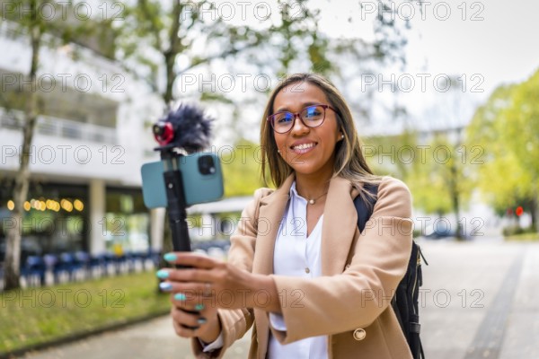 Stylish female latin vlogger smiling while recording new content in the city
