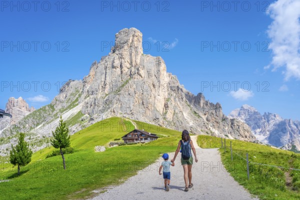 Mother and son walking on a path near the impressive giau pass in the italian dolomites, enjoying summer vacation