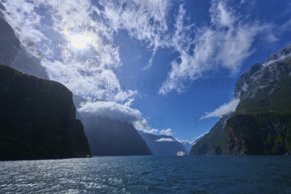 Sunny landscape with mountains and a ship in the distance, summer, Milford Sound, Te Anau, Fiordland National Park, South Island, New Zealand, Oceania