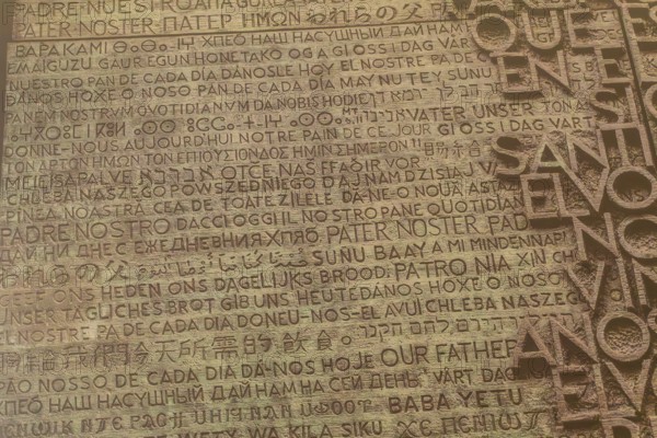Lord's prayer written in many different languages, creating a spiritual and multicultural tapestry on a textured background
