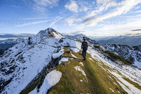 Mountaineer on hiking trail, mountain landscape with snow in autumn, summit and ridge of the Kramerspitz, Ammergau Alps, in autumn, Bavarian Alps, Bavaria, Germany, Europe