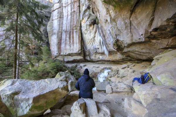 Hiker taking a break, frozen waterfall with icicles in the Gautschgrotte, Hohnstein, Saxony, Germany, Europe